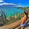 Vista de um mirante em Búzios, com uma mulher observando o mar azul e a vegetação ao redor, destacando o serviço de transfer do Rio de Janeiro para Búzios.