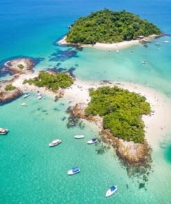 Vista aérea deslumbrante da Praia de Cataguases, em Angra dos Reis, com águas cristalinas, areia branca e várias embarcações ancoradas ao redor da ilha.